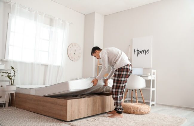 A man regularly flipping his mattress to prevent mould