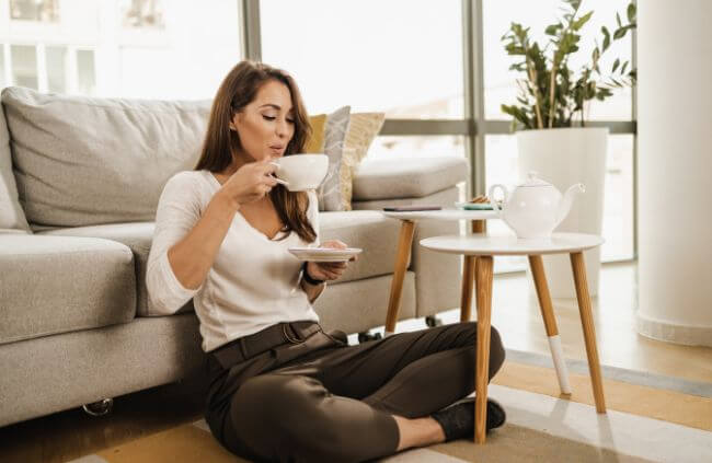A woman using a coaster to prevent coffee stain in her carpet